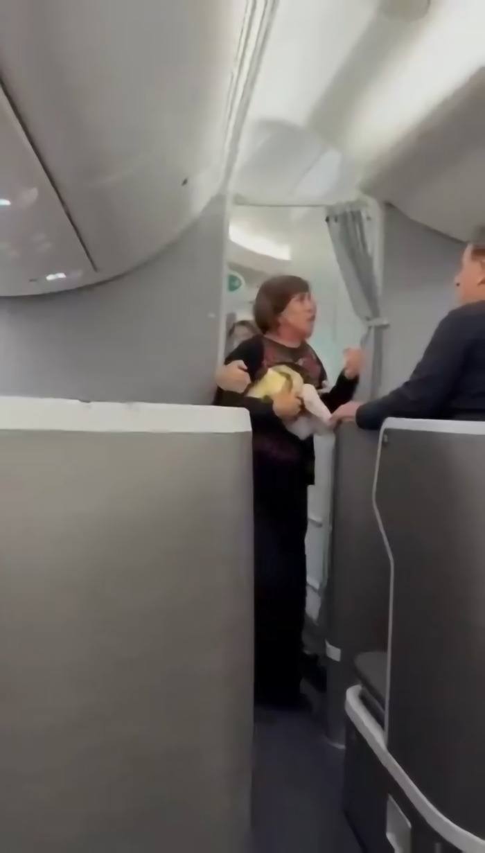 Woman confronts crew inside airplane cabin attempting to storm cockpit over flight delay dispute. Woman confronts crew inside airplane cabin attempting to storm cockpit over flight delay dispute.