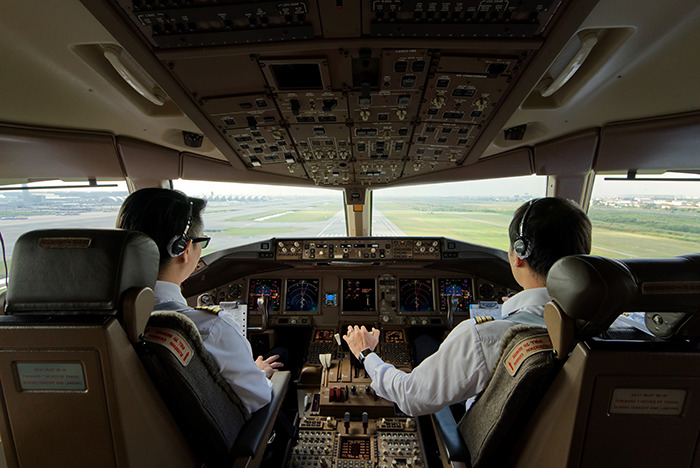 Two airline pilots in cockpit preparing for takeoff with flight delay disruption and crew intervention context. Two airline pilots in cockpit preparing for takeoff with flight delay disruption and crew intervention context.