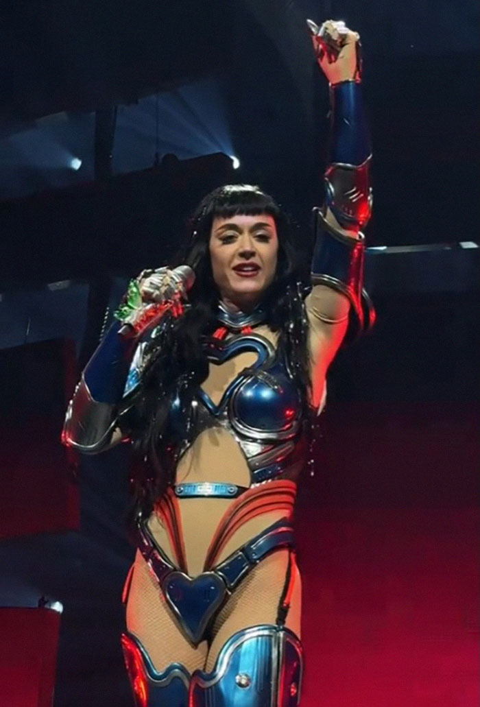 Singer performing on stage in a space-themed costume, showcasing unique "mom moves" during a tour debut. Singer performing on stage in a space-themed costume, showcasing unique "mom moves" during a tour debut.