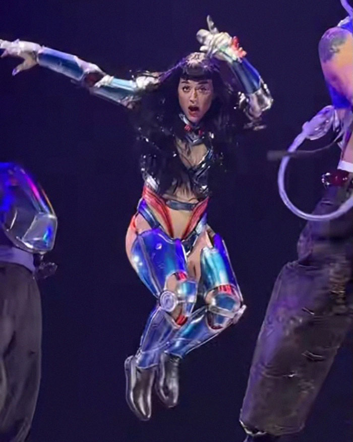Pop star in space-themed costume performing energetic dance moves on stage. Pop star in space-themed costume performing energetic dance moves on stage.