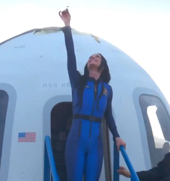 Woman in blue astronaut suit reaching upwards outside a capsule, symbolizing support for Katy Perry. Woman in blue astronaut suit reaching upwards outside a capsule, symbolizing support for Katy Perry.