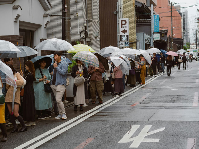 People standing in line with umbrellas, possibly waiting for the new KFC 'finger-licking' toothpaste. People standing in line with umbrellas, possibly waiting for the new KFC 'finger-licking' toothpaste.