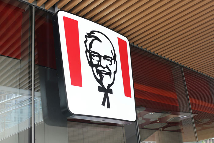 KFC logo sign on building exterior, highlighting the brand's iconic image and new 11 herbs and spices toothpaste launch. KFC logo sign on building exterior, highlighting the brand's iconic image and new 11 herbs and spices toothpaste launch.