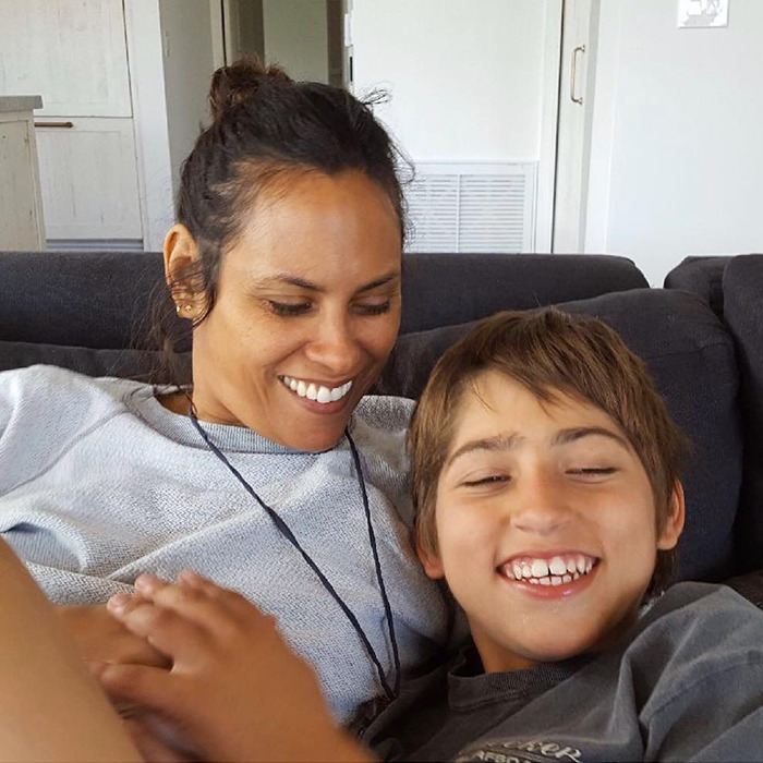A woman and a boy smiling and relaxing on a couch, showcasing a warm and joyful moment, related to Colin Farrell's parenting. A woman and a boy smiling and relaxing on a couch, showcasing a warm and joyful moment, related to Colin Farrell's parenting.