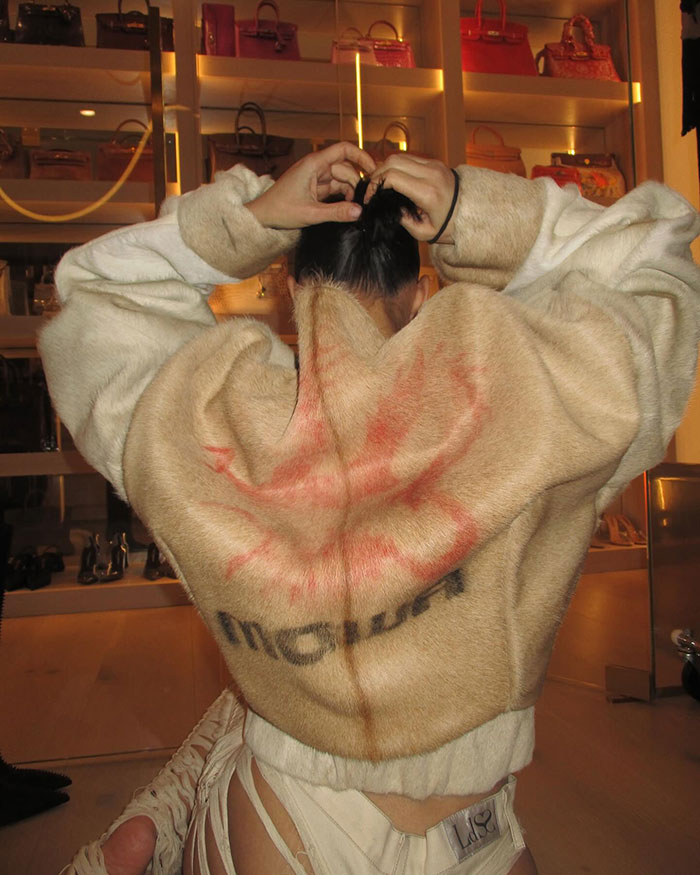 Woman in a furry coat adjusts her hair; shelves with handbags in the background. Woman in a furry coat adjusts her hair; shelves with handbags in the background.