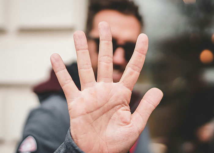 Person holding up hand, blocking view, symbolizing boundaries on money and bachelorette costs. Person holding up hand, blocking view, symbolizing boundaries on money and bachelorette costs.