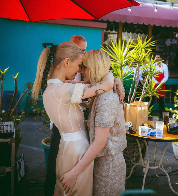 Lovebirds embrace at an outdoor wedding, sharing an intimate moment under a red umbrella. Lovebirds embrace at an outdoor wedding, sharing an intimate moment under a red umbrella.