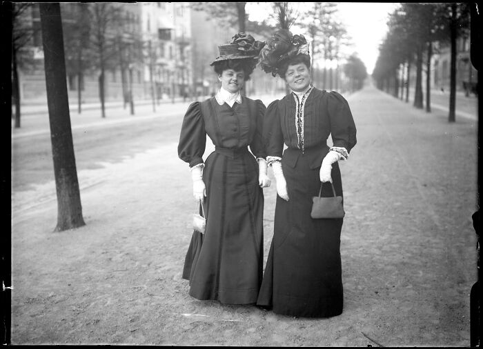 Two women in vintage dresses and hats posing outdoors in a rare photograph rescued from glass negatives.