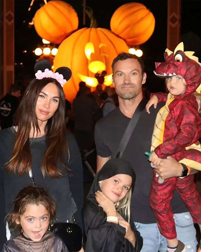 Family at a theme park with a Mickey pumpkin backdrop, including kids in costumes; related to Machine Gun Kelly. Family at a theme park with a Mickey pumpkin backdrop, including kids in costumes; related to Machine Gun Kelly.