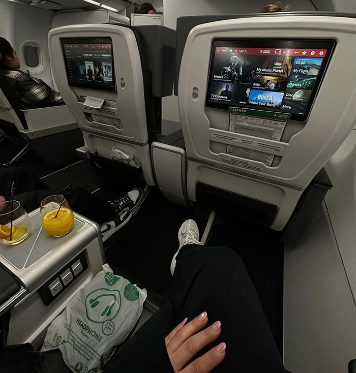 Airplane cabin with screens and drinks, related to a family's search for a buried loved one. Airplane cabin with screens and drinks, related to a family's search for a buried loved one.