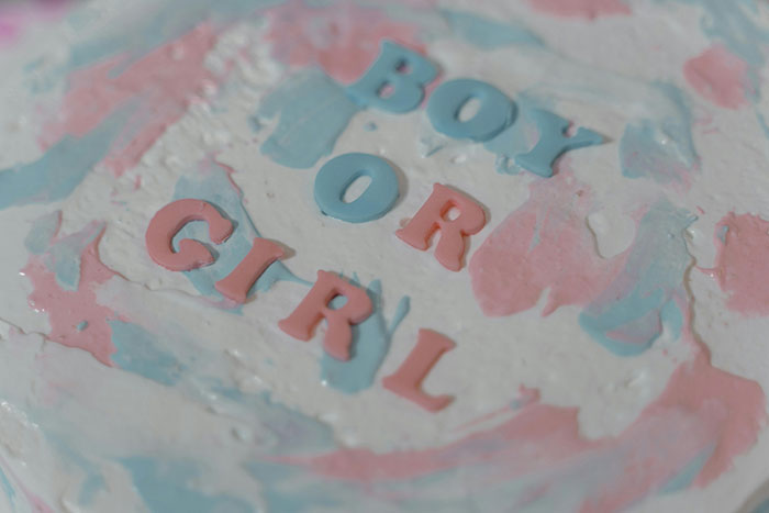 Close-up of a gender reveal cake with pink and blue icing spelling out boy or girl predicting pregnant friend’s baby gender. Close-up of a gender reveal cake with pink and blue icing spelling out boy or girl predicting pregnant friend’s baby gender.
