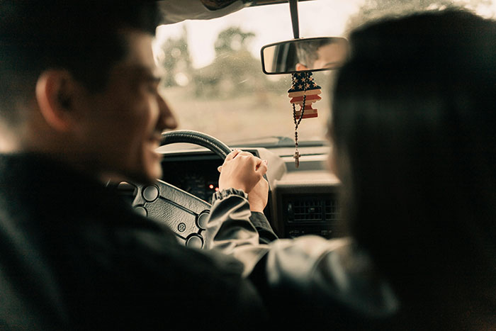 Man and woman holding hands inside a car, symbolizing support amid statistics predicting pregnant friend will have a boy. Man and woman holding hands inside a car, symbolizing support amid statistics predicting pregnant friend will have a boy.