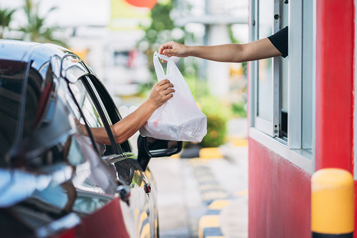 Driver receives a takeout bag at a drive-thru, illustrating a moment of petty revenge against an arrogant driver. Driver receives a takeout bag at a drive-thru, illustrating a moment of petty revenge against an arrogant driver.