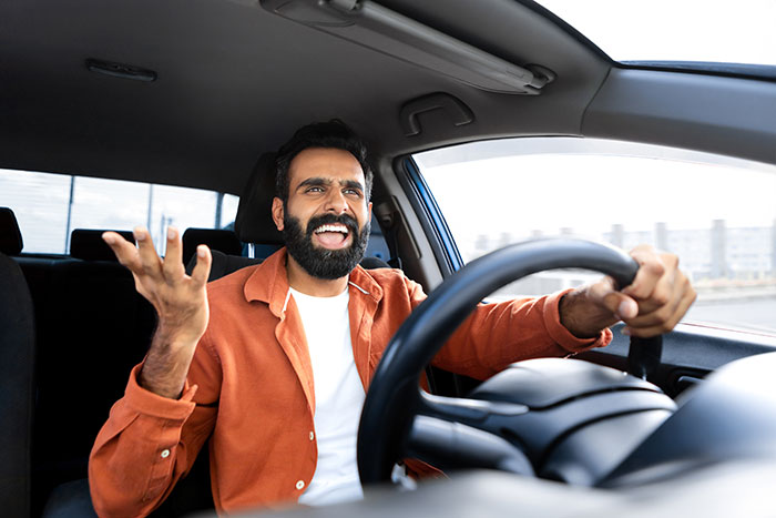 Arrogant driver gestures wildly behind the wheel, showing frustration. Arrogant driver gestures wildly behind the wheel, showing frustration.