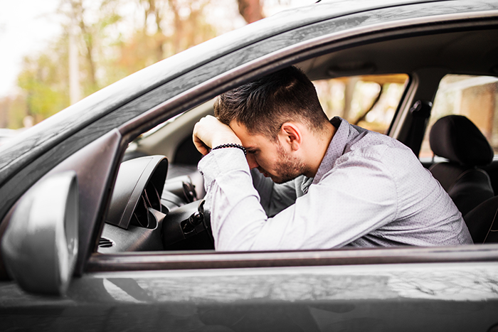 Man sitting in a car, visibly upset, resting his head on the steering wheel. Man sitting in a car, visibly upset, resting his head on the steering wheel.