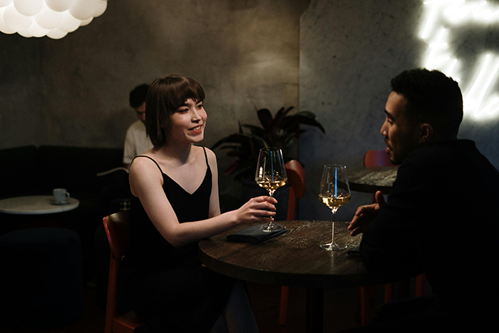 Couple at a restaurant table with wine glasses, woman talking, man listening attentively. Couple at a restaurant table with wine glasses, woman talking, man listening attentively.