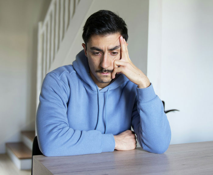 Man in blue hoodie, deep in thought, contemplating divorce after wife's actions. Man in blue hoodie, deep in thought, contemplating divorce after wife's actions.