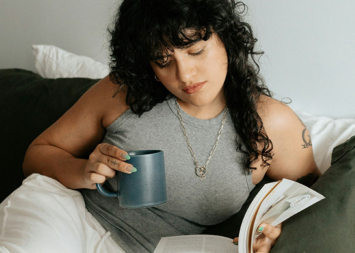 Woman relaxing with a book and coffee, illustrating feelings of not being a team player. Woman relaxing with a book and coffee, illustrating feelings of not being a team player.