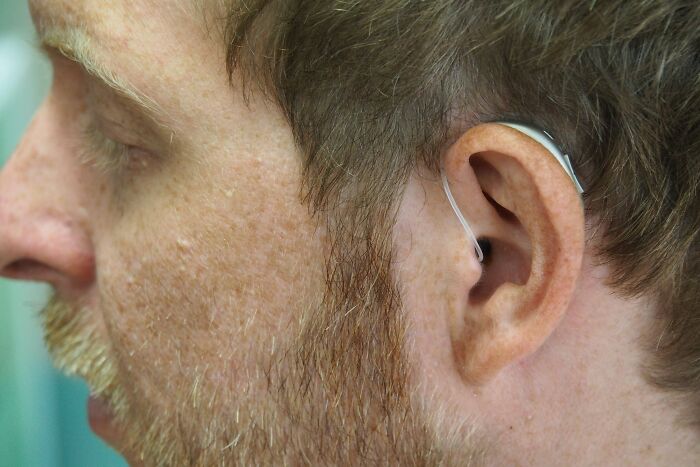 Close-up of a man's ear with a hearing aid, highlighting adult tantrums and challenges related to hearing issues.