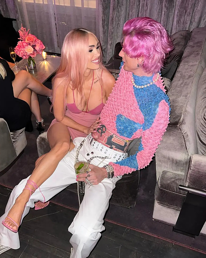 Couple with pink hair and outfits sitting closely, sharing a moment in a stylish lounge. Couple with pink hair and outfits sitting closely, sharing a moment in a stylish lounge.