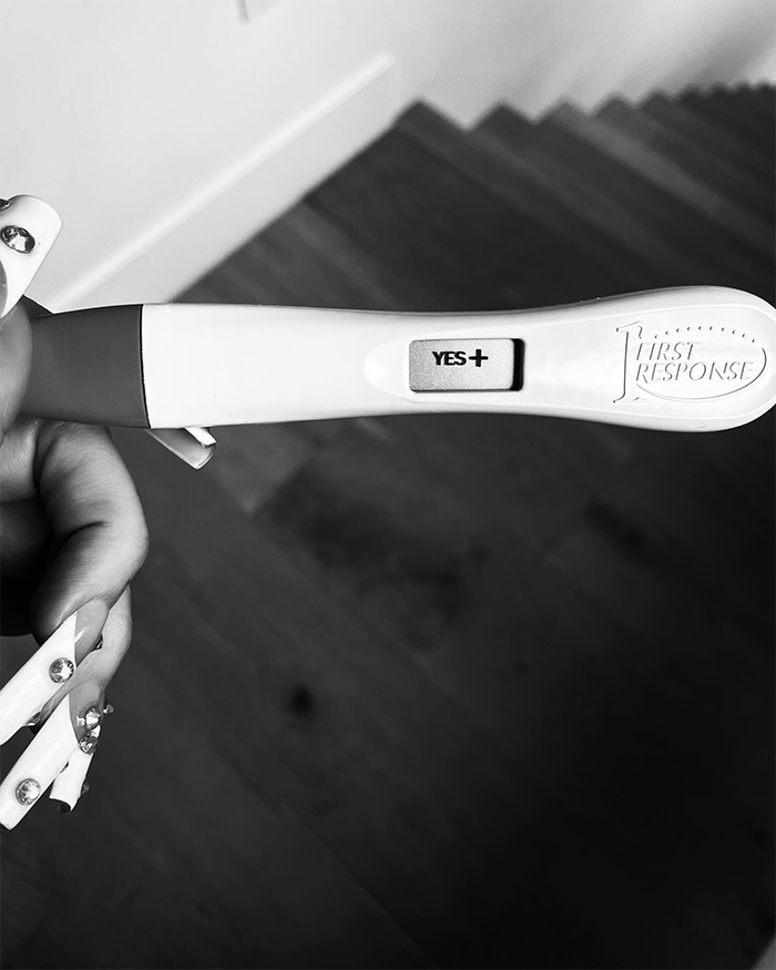 Positive pregnancy test held by person with long nails, related to Machine Gun Kelly and Megan Fox baby name confusion. Positive pregnancy test held by person with long nails, related to Machine Gun Kelly and Megan Fox baby name confusion.