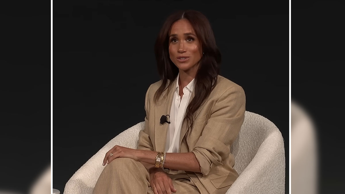 Meghan Markle speaking in a beige suit during an interview, discussing her kids with red hair traits.