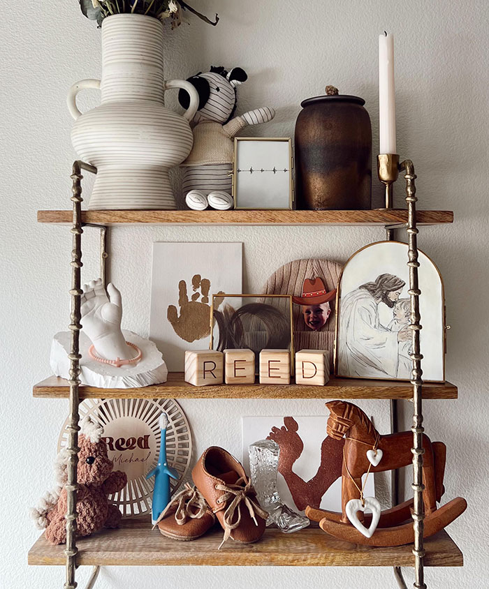 Memorial shelf for parenting influencer's son with toys, handprint art, and framed pictures. Memorial shelf for parenting influencer's son with toys, handprint art, and framed pictures.