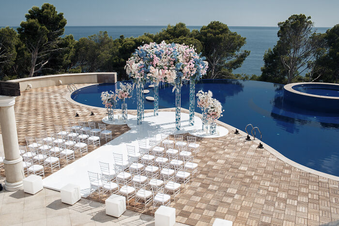 Outdoor wedding setup by a pool with floral decorations, highlighting generational changes affecting the joy of weddings. Outdoor wedding setup by a pool with floral decorations, highlighting generational changes affecting the joy of weddings.