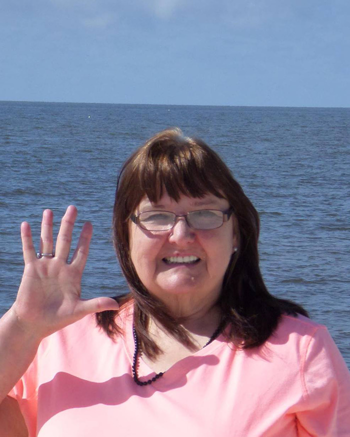 Woman in glasses and pink shirt smiling by the sea, associated with "evil" mom case. Woman in glasses and pink shirt smiling by the sea, associated with "evil" mom case.