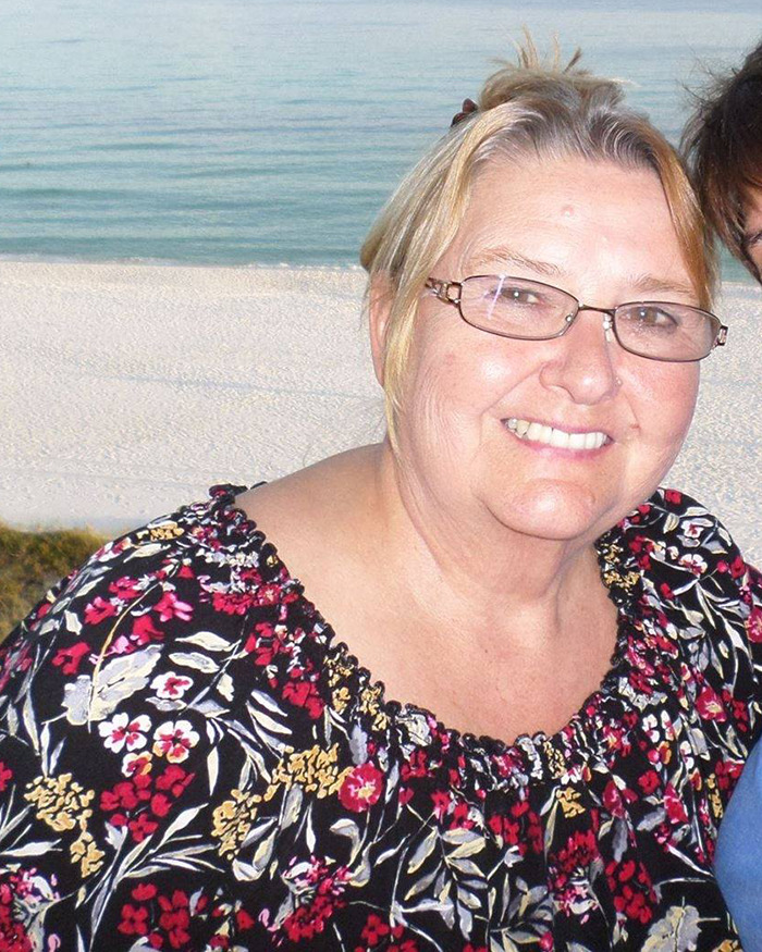 Smiling woman in glasses with floral blouse, beachfront background. Smiling woman in glasses with floral blouse, beachfront background.