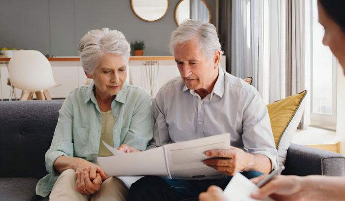 Elderly couple reviewing documents on a couch, discussing moral grounds related to an inheritance. Elderly couple reviewing documents on a couch, discussing moral grounds related to an inheritance.