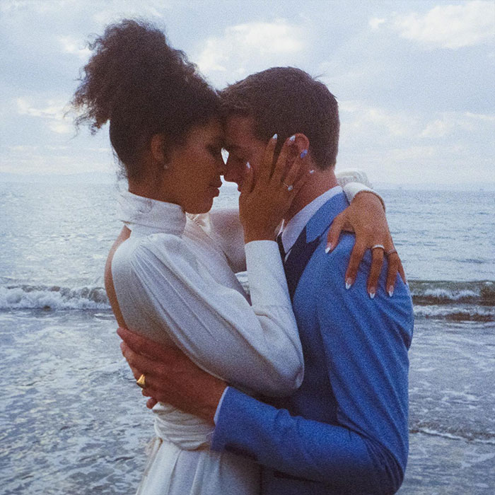 A couple embracing by the sea, showcasing youth and serenity in a tender moment.