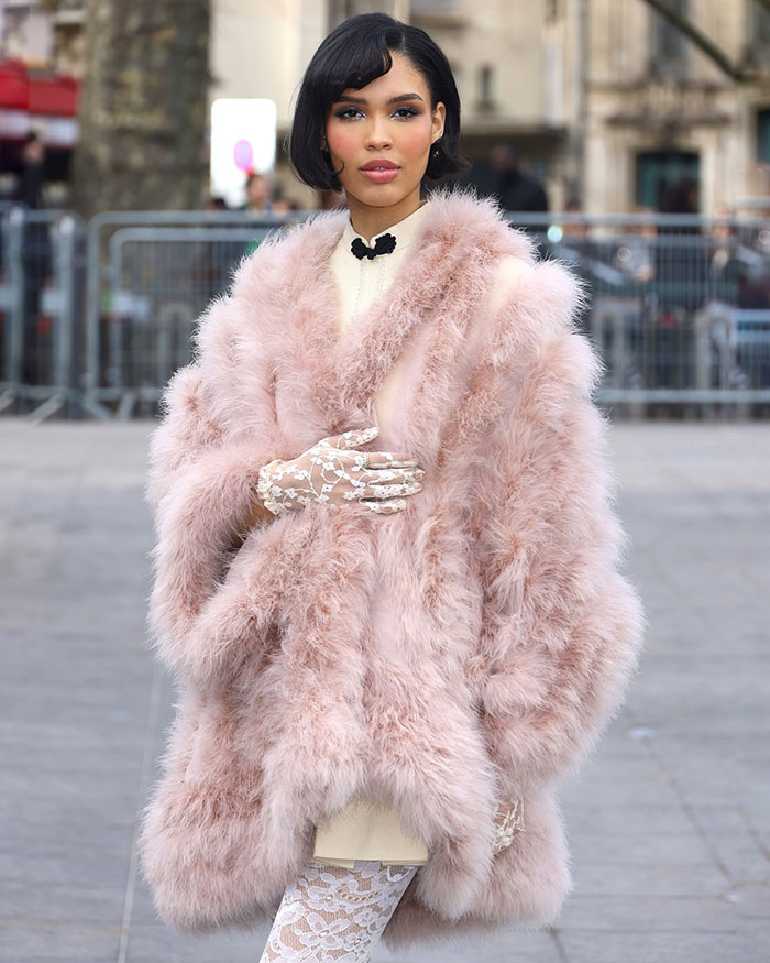 Nara Smith in pink fur coat, exuding calm and composure, standing confidently in an outdoor setting.