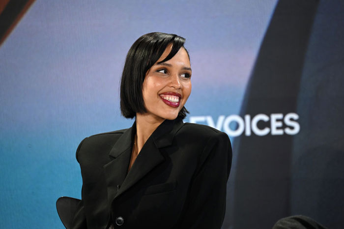 Young and composed Nara Smith smiling in a black blazer during a public event.