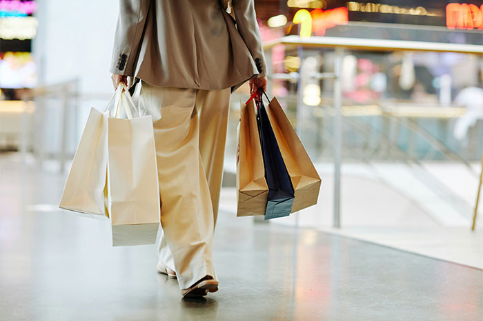 Person carrying several shopping bags in a mall, highlighting consumerism challenge prior to "No-Buy 2025. Person carrying several shopping bags in a mall, highlighting consumerism challenge prior to "No-Buy 2025.