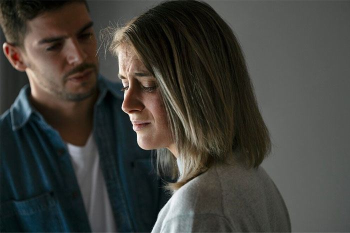 Woman looks distressed, man in background, highlighting relationship conflict over lost love. Woman looks distressed, man in background, highlighting relationship conflict over lost love.