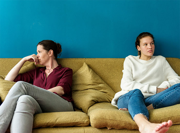 Two women sitting apart on a couch, looking upset and refusing to reconcile after a conflict over a man. Two women sitting apart on a couch, looking upset and refusing to reconcile after a conflict over a man.