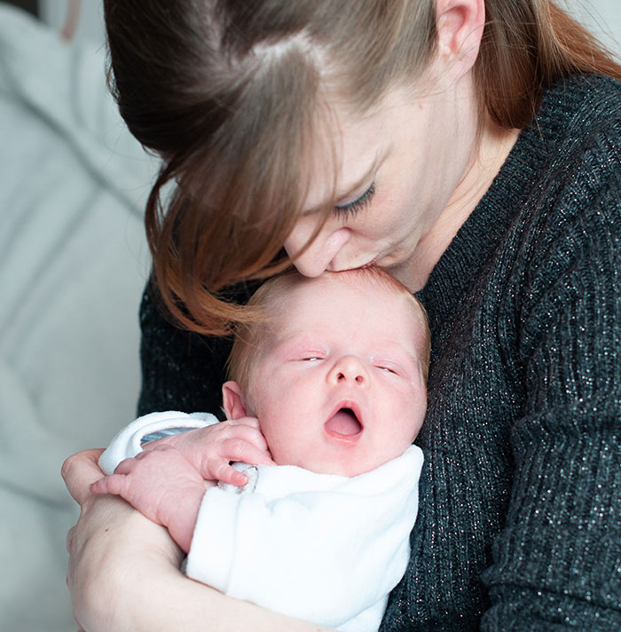 A mother lovingly holds her newborn baby, showcasing the bond between parent and child. A mother lovingly holds her newborn baby, showcasing the bond between parent and child.