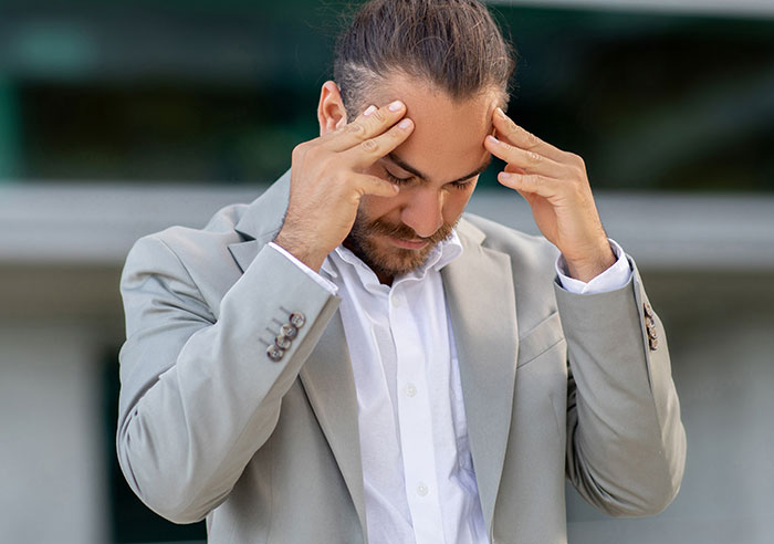 Man in a beige suit, looking troubled, hands on forehead, representing a dilemma about his female best friend and child's birth. Man in a beige suit, looking troubled, hands on forehead, representing a dilemma about his female best friend and child's birth.