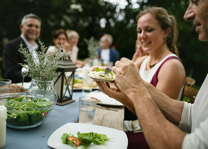 Guests enjoying a vegetarian meal at a wedding reception, smiling and chatting around a table. Guests enjoying a vegetarian meal at a wedding reception, smiling and chatting around a table.