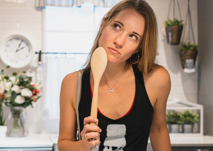 Woman in a kitchen pondering with a wooden spoon, relating to vegetarian meatballs incident. Woman in a kitchen pondering with a wooden spoon, relating to vegetarian meatballs incident.