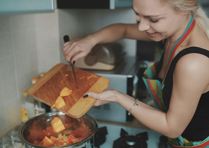 Woman in kitchen preparing vegetarian dish with cutting board and pot. Woman in kitchen preparing vegetarian dish with cutting board and pot.