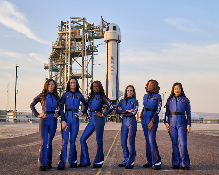 Crew in blue jumpsuits standing in front of Blue Origin capsule, conspiracy theorists claim "fake" hand seen. Crew in blue jumpsuits standing in front of Blue Origin capsule, conspiracy theorists claim "fake" hand seen.