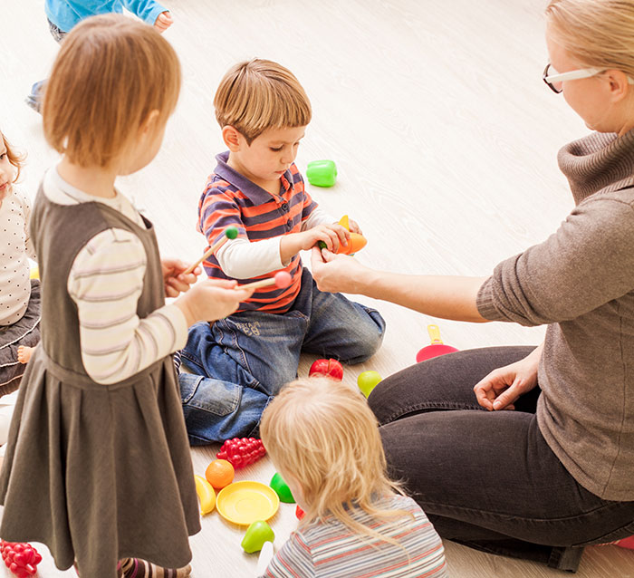Children playing with colorful toys in a classroom setting, engaging with a teacher. Children playing with colorful toys in a classroom setting, engaging with a teacher.