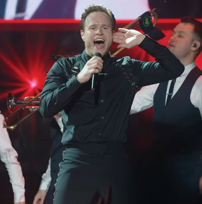 Singer performing on stage in black outfit, highlighting physique transformation that sparked debate between men and women. Singer performing on stage in black outfit, highlighting physique transformation that sparked debate between men and women.