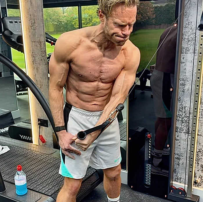 Muscular singer showing physique transformation while working out with cable machine in a gym setting. Muscular singer showing physique transformation while working out with cable machine in a gym setting.