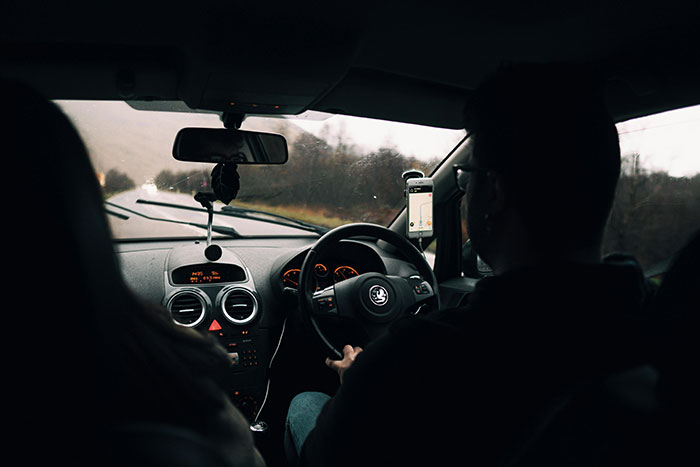 Man driving on a road trip, possibly visiting a long-distance girlfriend, with a GPS visible on the dashboard. Man driving on a road trip, possibly visiting a long-distance girlfriend, with a GPS visible on the dashboard.