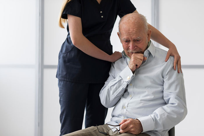Elderly patient sitting, comforted by a nurse, looking contemplative in a clinical setting. Elderly patient sitting, comforted by a nurse, looking contemplative in a clinical setting.