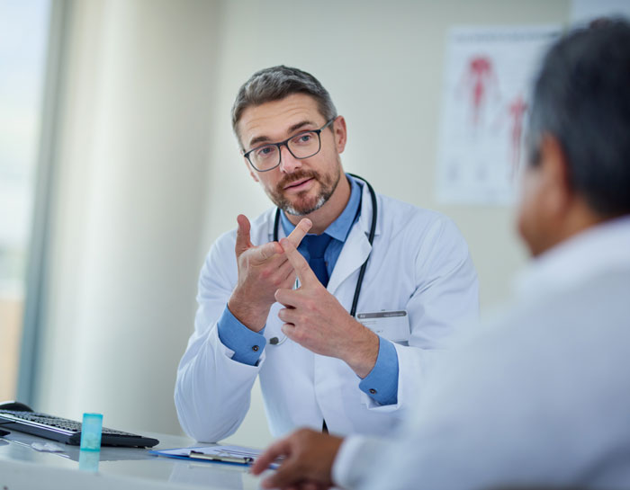 Doctor in discussion with a patient, gesturing with hands, wearing a white coat and stethoscope. Doctor in discussion with a patient, gesturing with hands, wearing a white coat and stethoscope.