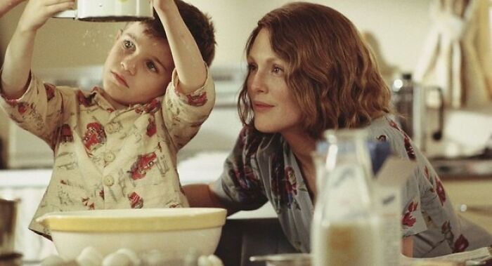 A child in pajamas cooks with a woman, evoking emotions linked to tear-inducing movies.